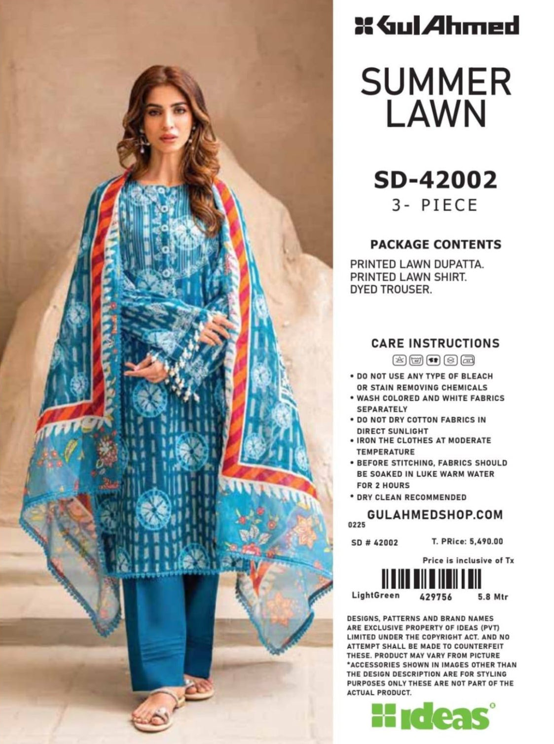 Woman wearing a blue printed outfit with a dupatta, standing against a beige wall with 'Gul Ahmed' branding.